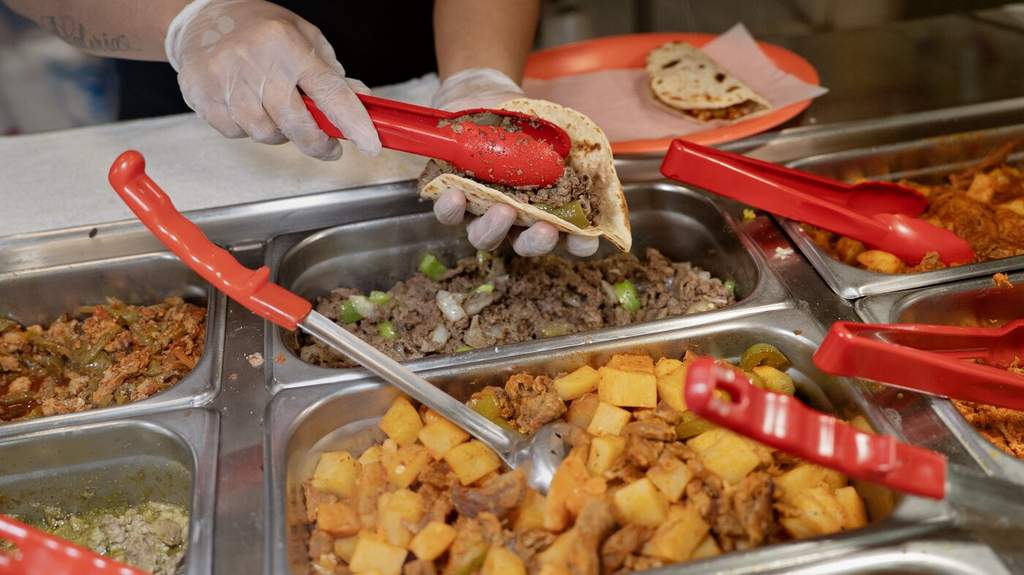 Pekerja di kedai Monchy's di Houston sedang menyiapkan pesanan taco daging sapi untuk pelanggan.