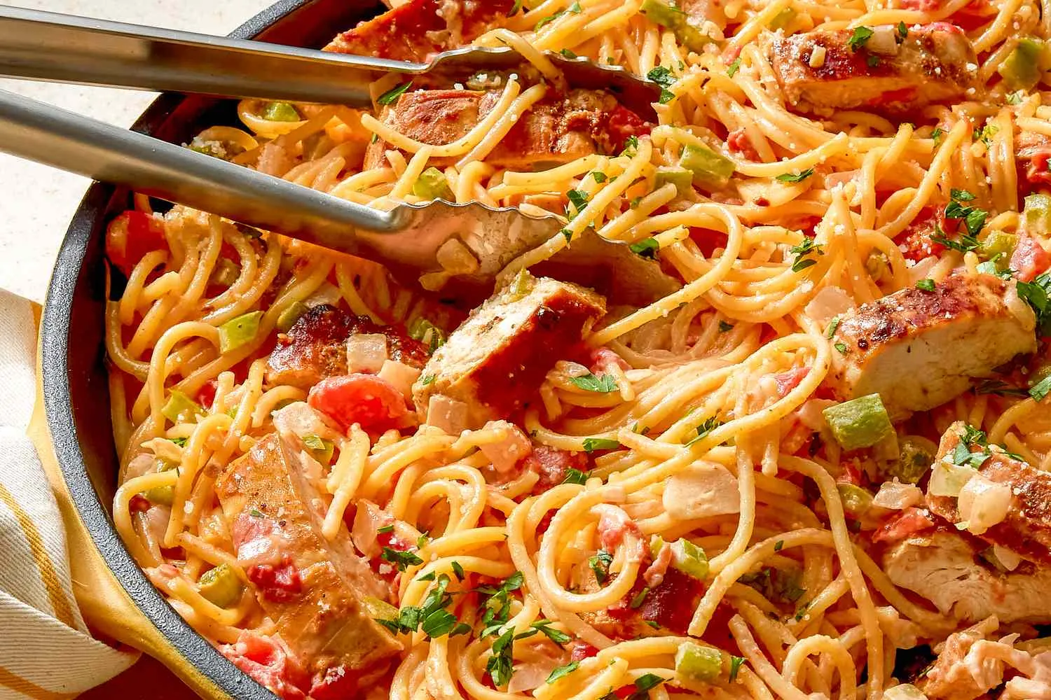 Piring berisi Creamy Cajun Chicken Spaghetti hangat dengan taburan parmesan