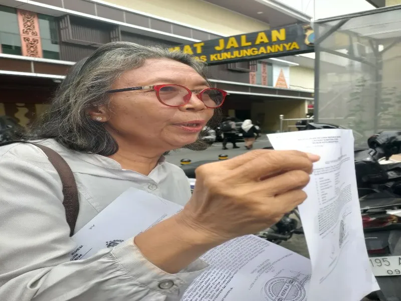 Pengacara Dameria Sagala menunjukkan berkas laporan di Polrestabes Medan