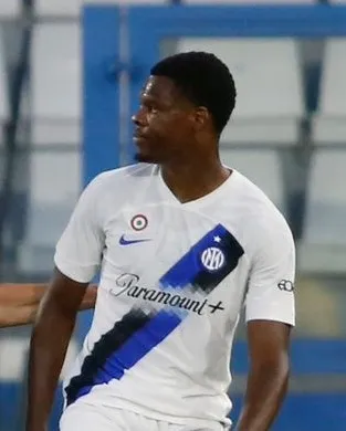 Foto Denzel Dumfries mengenakan seragam sepak bola dengan ekspresi fokus di lapangan