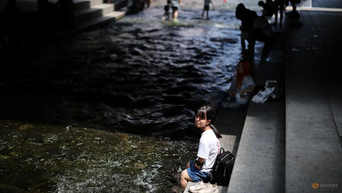 Seorang warga mendinginkan kaki di Sungai Cheonggye saat gelombang panas ekstrem di Seoul