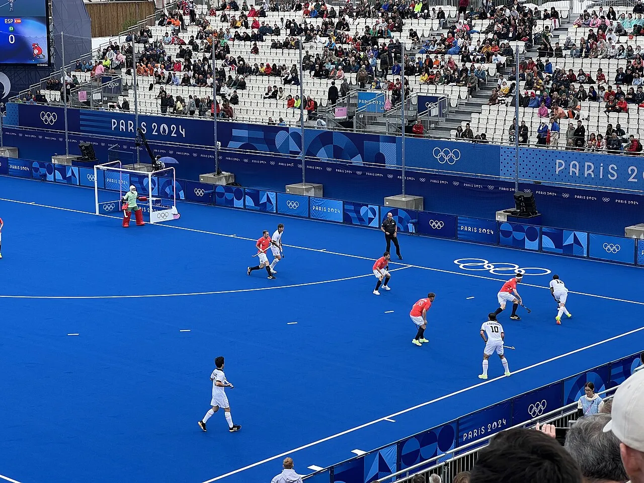 Pemain field hockey sedang menggiring bola dengan stik di lapangan hijau