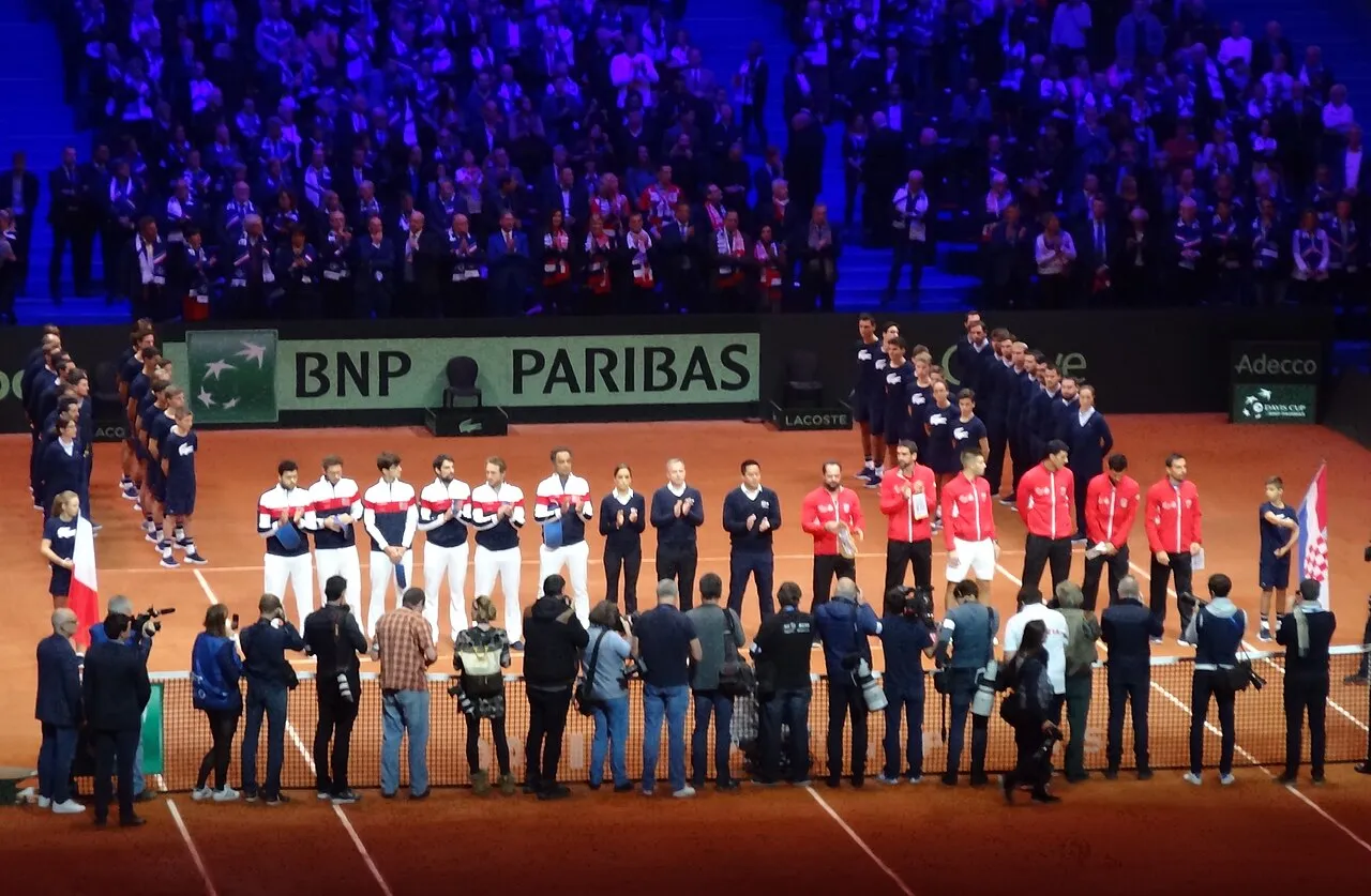 Trofi Davis Cup dan pemain tenis yang merayakan kemenangan di lapangan