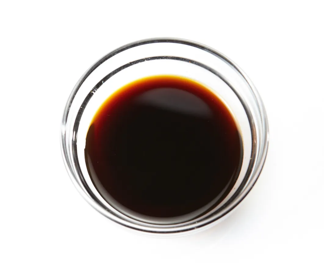 Botol dan mangkuk berisi kecap asin cair dengan warna gelap yang siap digunakan untuk memasak