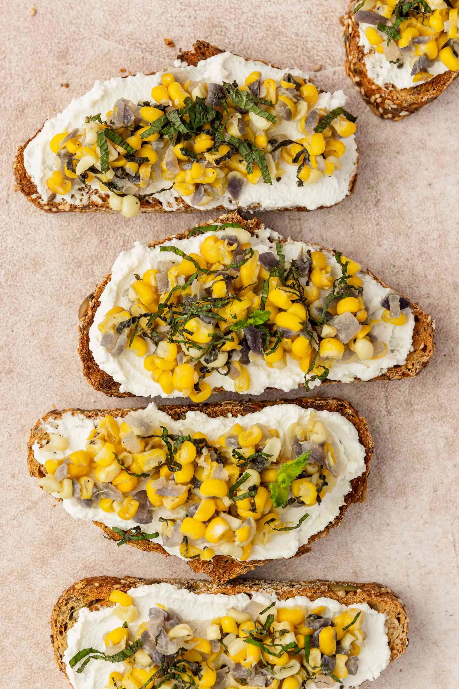 Corn and ricotta bruschetta di atas piring saji dengan taburan mint