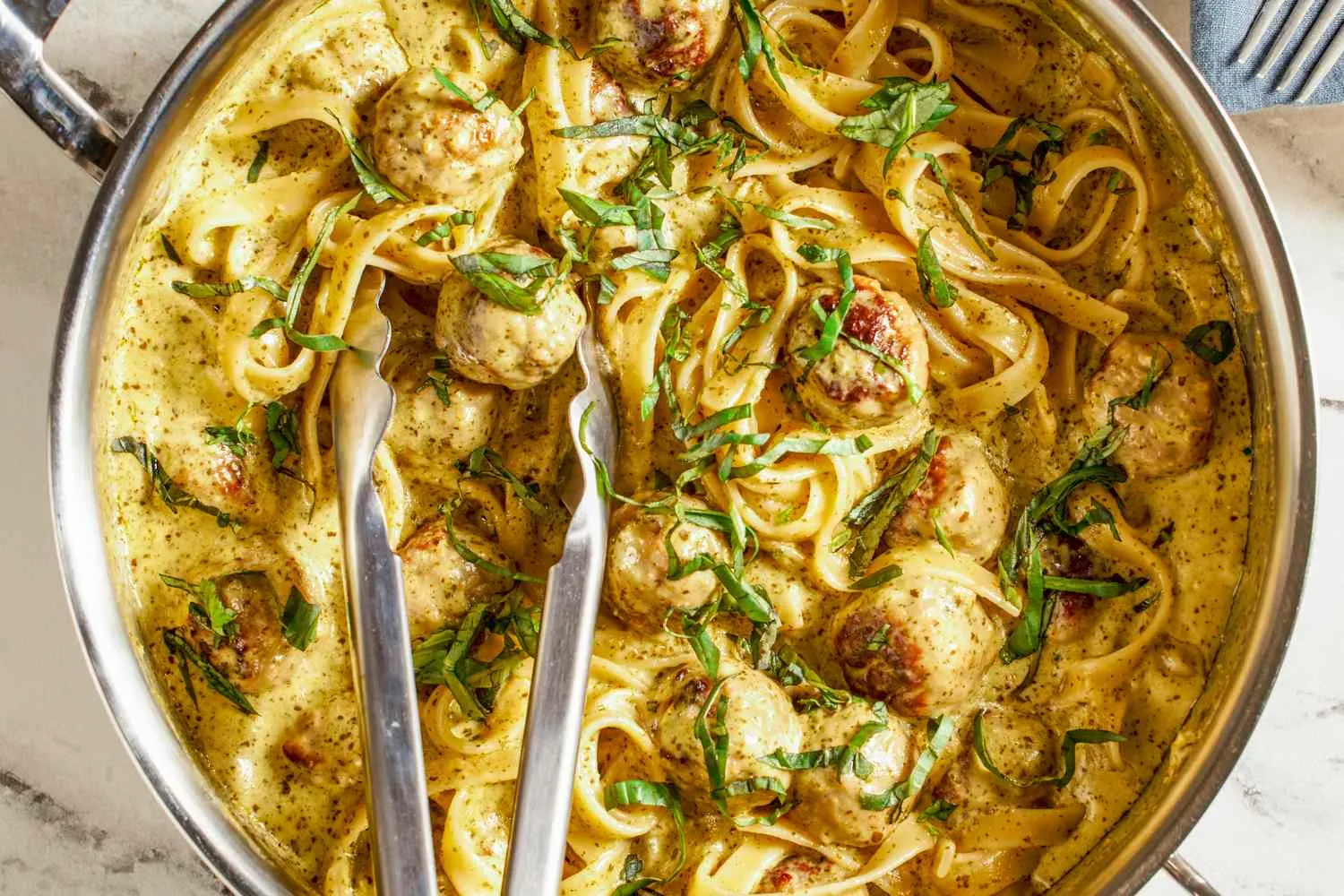 Meatball Pesto Pasta dengan taburan keju parmesan dan daun basil segar