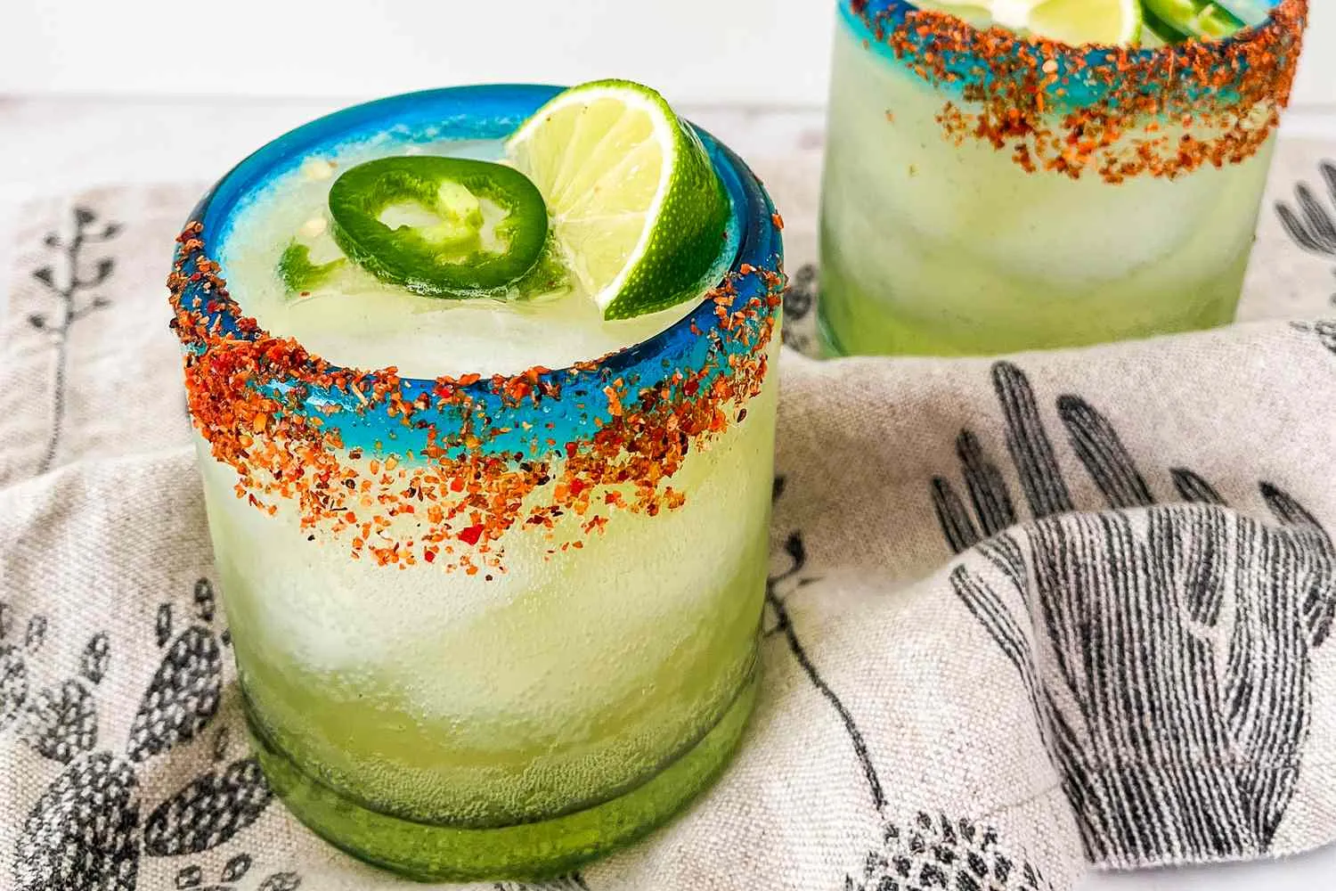 Segelas spicy margarita mocktail segar dengan hiasan irisan jeruk nipis dan jalapeño