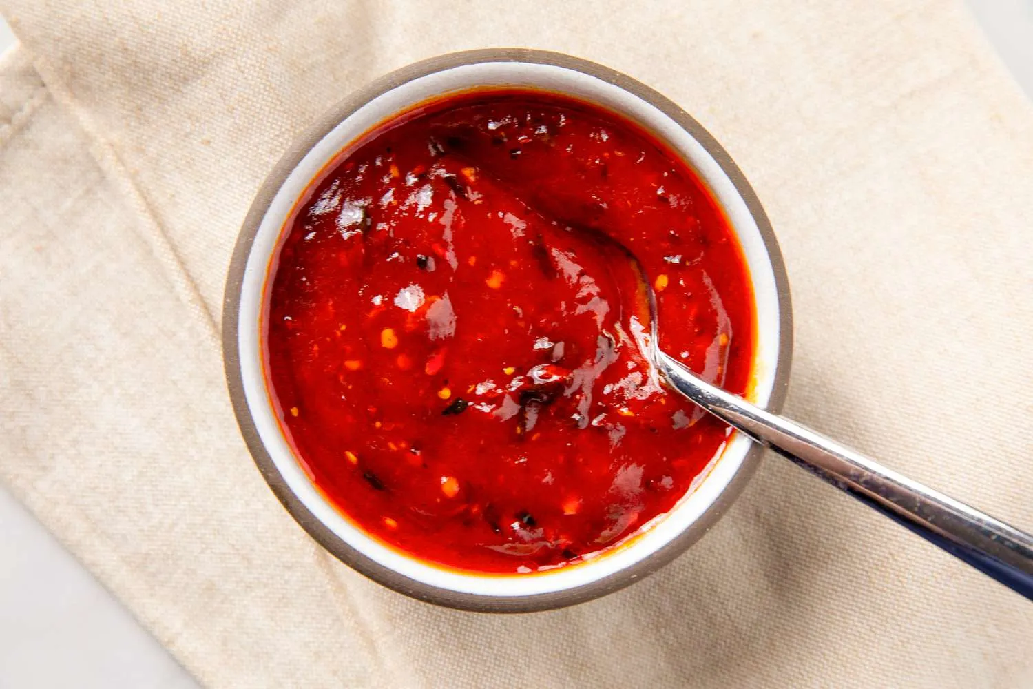 Mangkuk berisi spicy sweet and sour sauce kental dengan warna merah cerah