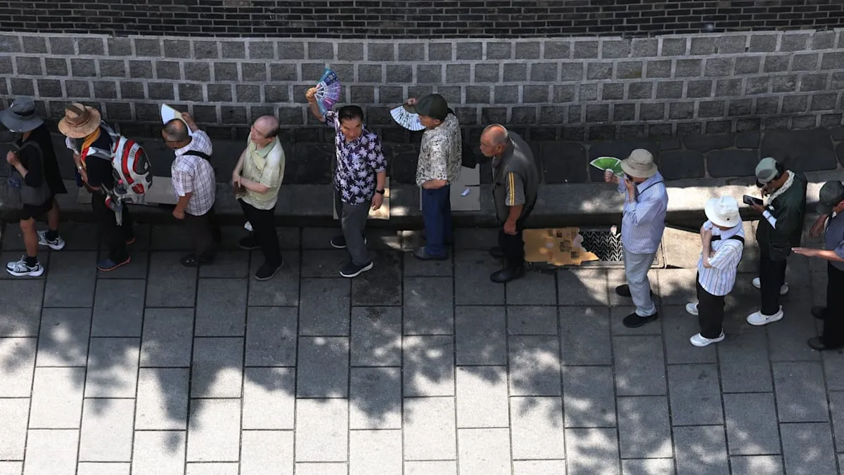 Warga lanjut usia mengantre untuk mendapatkan makanan gratis di sebuah taman di Seoul di tengah gelombang panas ekstrem.